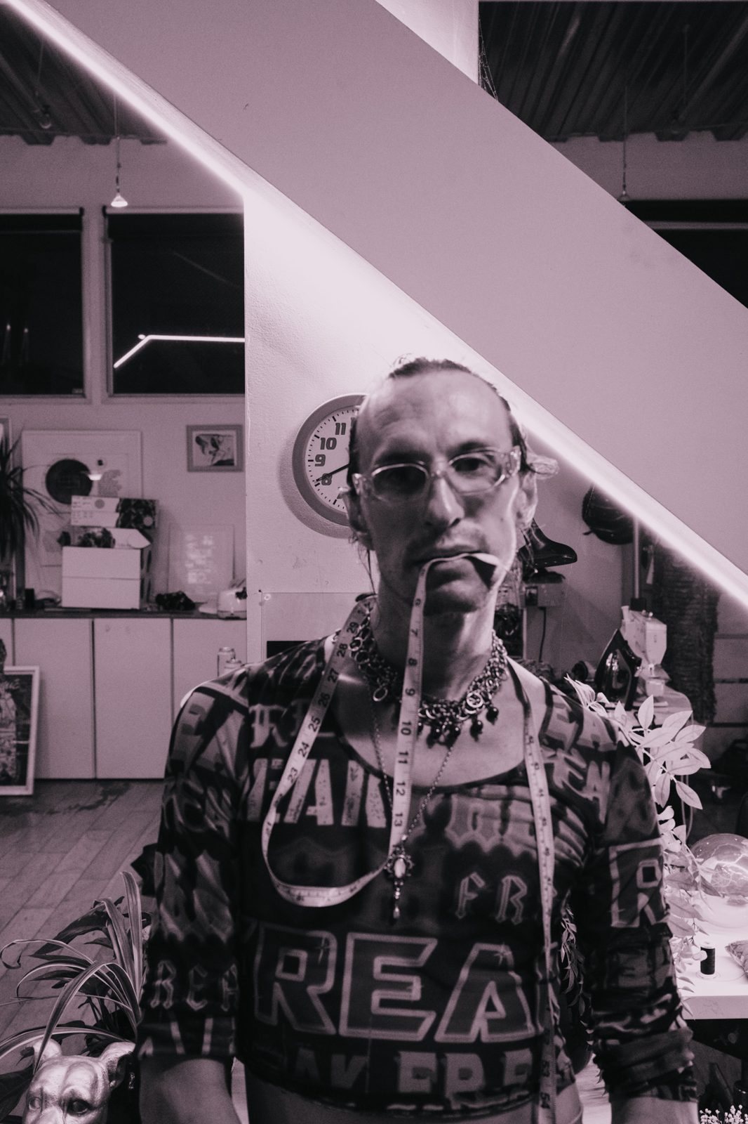 Designer in clear glasses with a tape measure hanging from his mouth