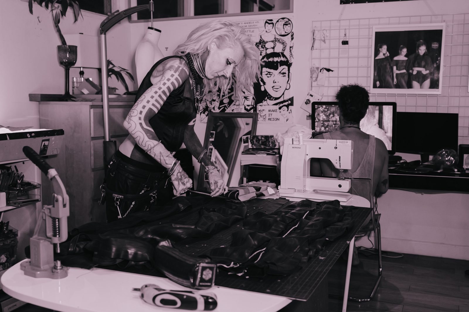 Designer cutting leather panels with a sewing machine and comic posters behind