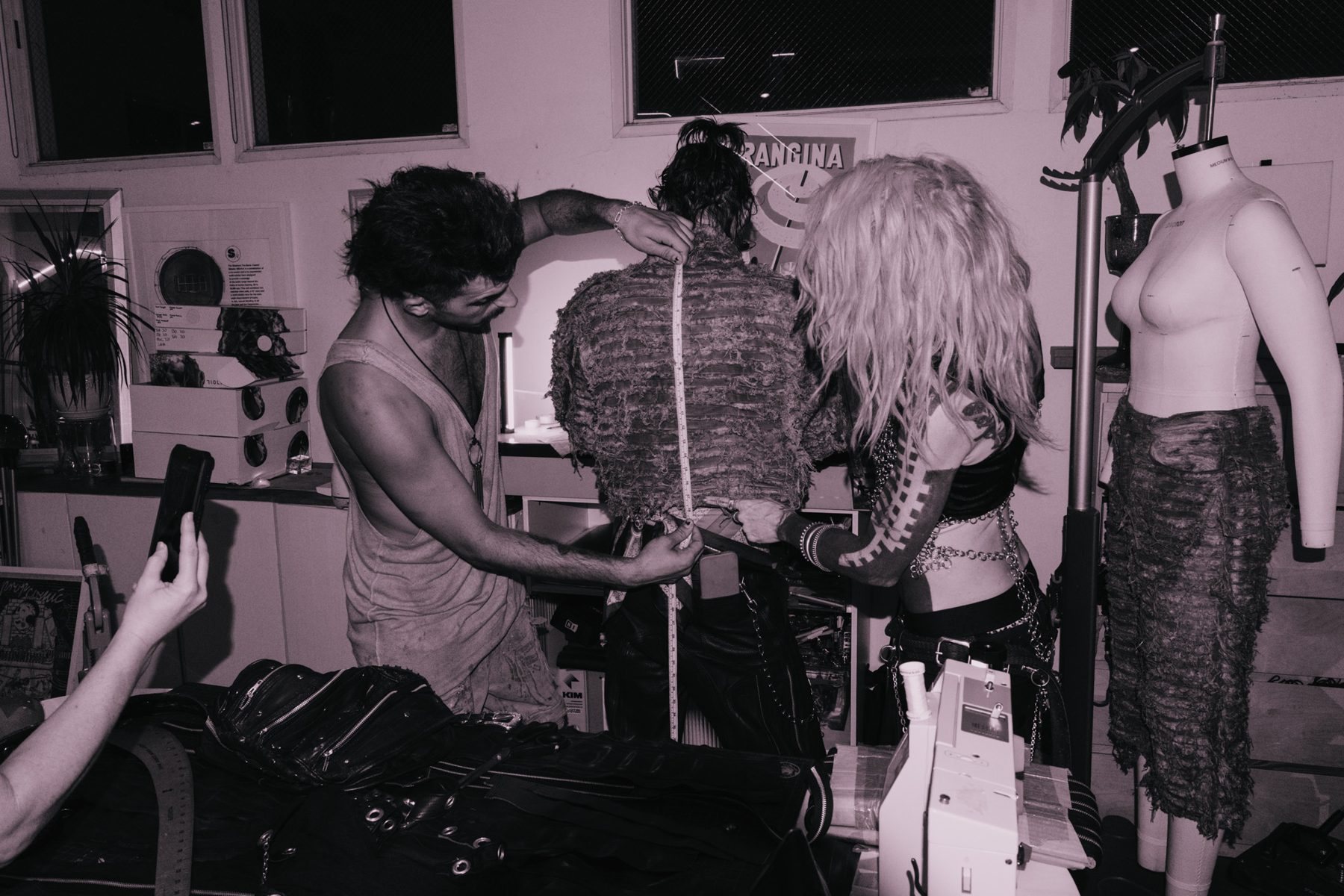 Designers running a tape measure down the back of a shredded jacket